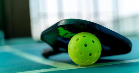 Pickleball paddle and neon green ball