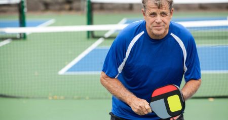 Man holding a pickleball paddle on a pickleball court
