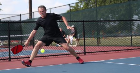Is Pickleball the Fastest Growing Sport? Man in a black shirt playing pickleball on an outdoor court