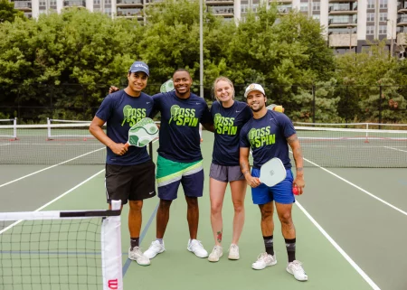 The Toss & Spin pickleball group is pictured on an outdoor court with rackets in-hand.